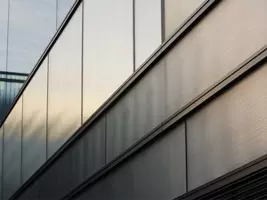 szkło przeciwsłoneczne, nowoczesna fasada budynku wykonanej z metalu i szkła. Panele szklane odbijają delikatne światło, tworząc subtelne gradienty i refleksy. Linie pionowe i poziome nadają konstrukcji minimalistyczny i industrialny charakter